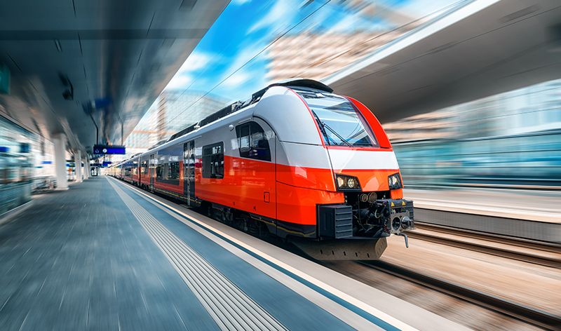 High speed train in motion on the train station at sunset in Vienna, Austria. Red modern intercity passenger train with motion blur effect. Railway platform. Railroad. Commercial transportation